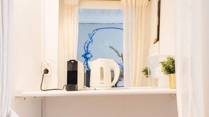Une petite salle de bain avec un lavabo blanc, un miroir au-dessus, une petite fenêtre avec des rideaux, un radiateur blanc et une poubelle.