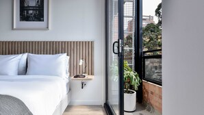 A modern bedroom with a bed, bedside table, lamp, and a view of the outside through a sliding door. - w Radiant Loft w Balcony in Chapinero (Bogotá)