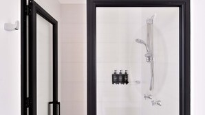 A modern bathroom with a glass shower enclosure, a black-framed door, and a wall-mounted soap dispenser. - w Radiant Loft w Balcony in Chapinero (Bogotá)
