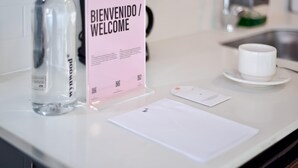 A reception desk with a welcome sign, a bottle of water, a white mug, and a notepad. - w Radiant Loft w Balcony in Chapinero (Bogotá)