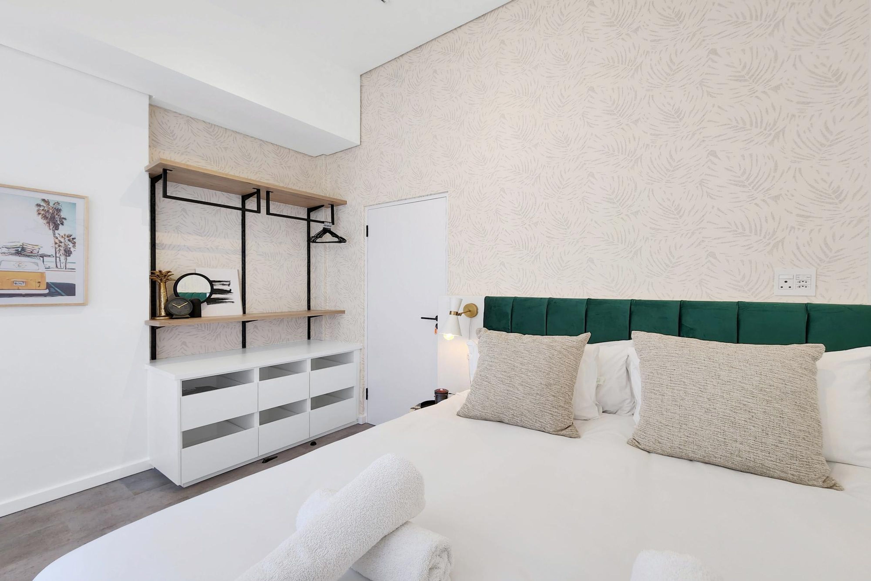 A modern bedroom with a bed, white storage unit, and a green headboard.