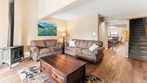 A spacious living room with a fireplace, two leather sofas, a wooden coffee table, and a painting on the wall.