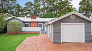A two-story house with a garage, a brick chimney, and a well-maintained lawn.