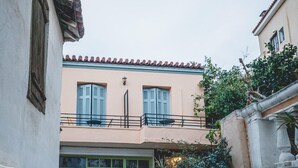 Una calle estrecha con un edificio que tiene un balcón y una tienda con una puerta verde.
