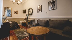 Un salón acogedor con una mesa redonda de madera, un sofá, una araña y decoración en las paredes.