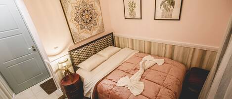 A hotel room with a bed, a nightstand, a lamp, and two framed pictures on the wall.