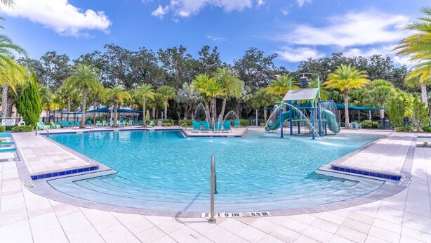 A swimming pool with a slide, surrounded by palm trees and lounge chairs. - 2614 Veranda Palms (Kissimmee)