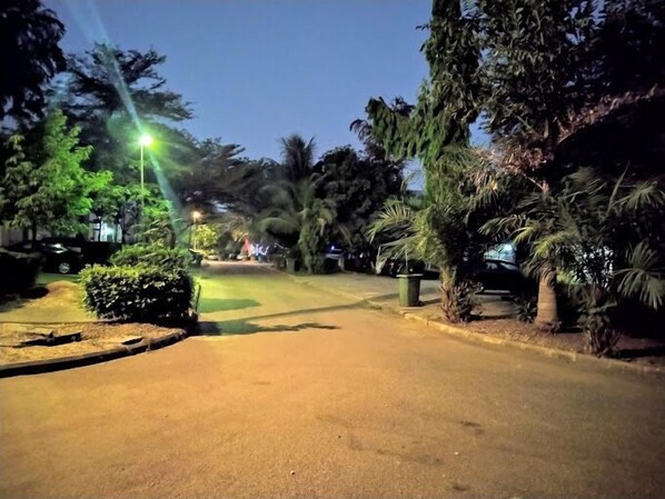 A nighttime street scene with streetlights, trees, and parked cars. - Cosmetro Shortlet Homes (Abuja)