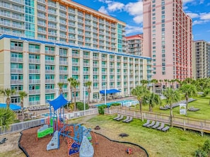 A hotel with multiple floors, a playground, and a pool area.