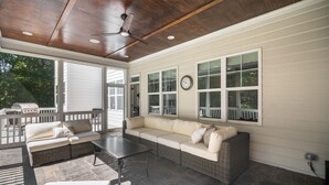 A covered patio with a wicker sofa, a table, and a ceiling fan. - Durham Retreat Games, Exercise, And Relaxation 5 Bedroom Home (Durham)