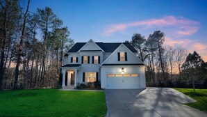 A two-story house with a garage, a front porch, and a well-maintained lawn. - Durham Retreat Games, Exercise, And Relaxation 5 Bedroom Home (Durham)