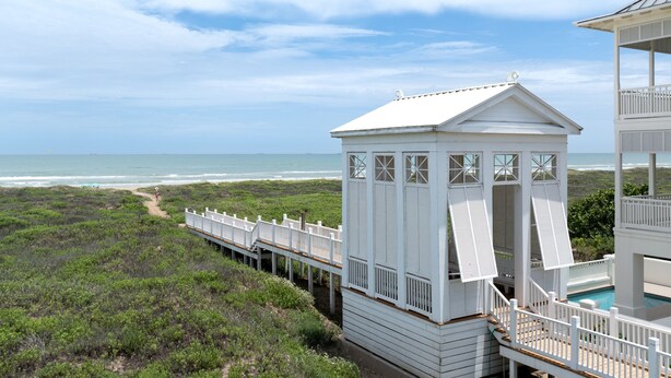 Un edificio costiero con una terrazza che si affaccia su un sentiero sulla spiaggia, con vista sull'oceano.
