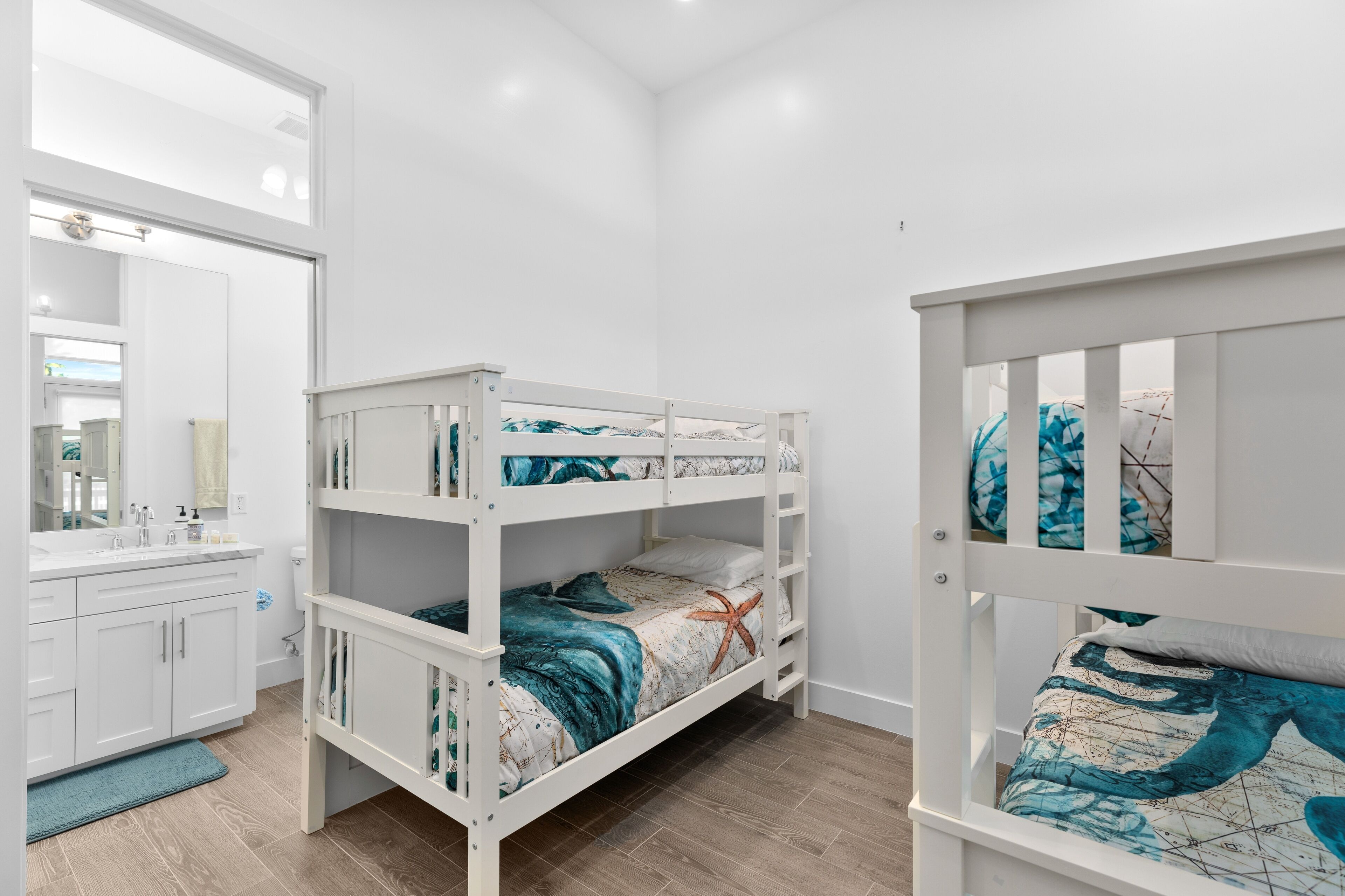 A bunk bed room with a bathroom and a mirror.