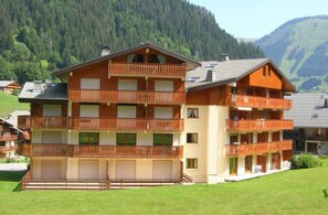 A multi-story building with balconies, a flat roof, and a grassy lawn. - Violettes VL2 Telecabine & Nature 4 Pers (Chatel)
