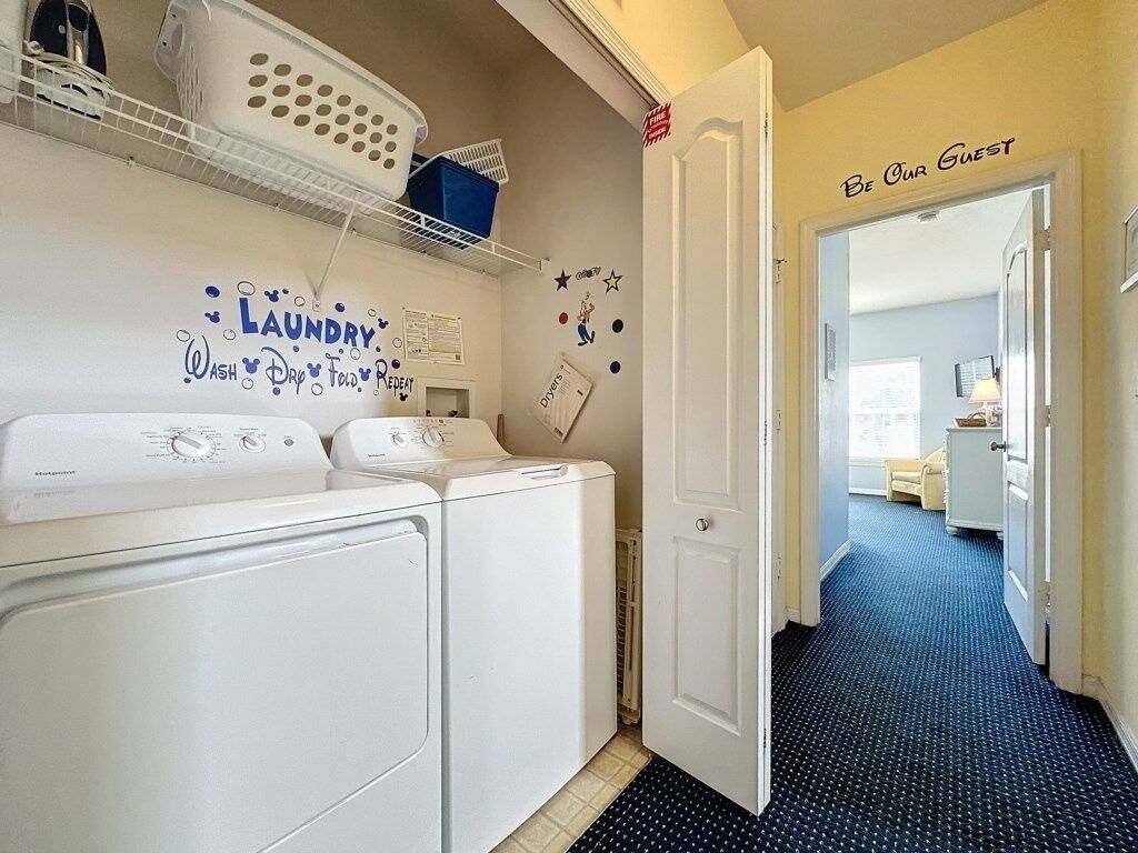 A laundry area with a washing machine, dryer, and a shelf with laundry baskets. A door with a sign reading "Be Our Guest" is visible.