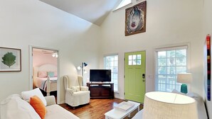 Una sala de estar moderna con un sofá blanco, una puerta verde y un televisor.