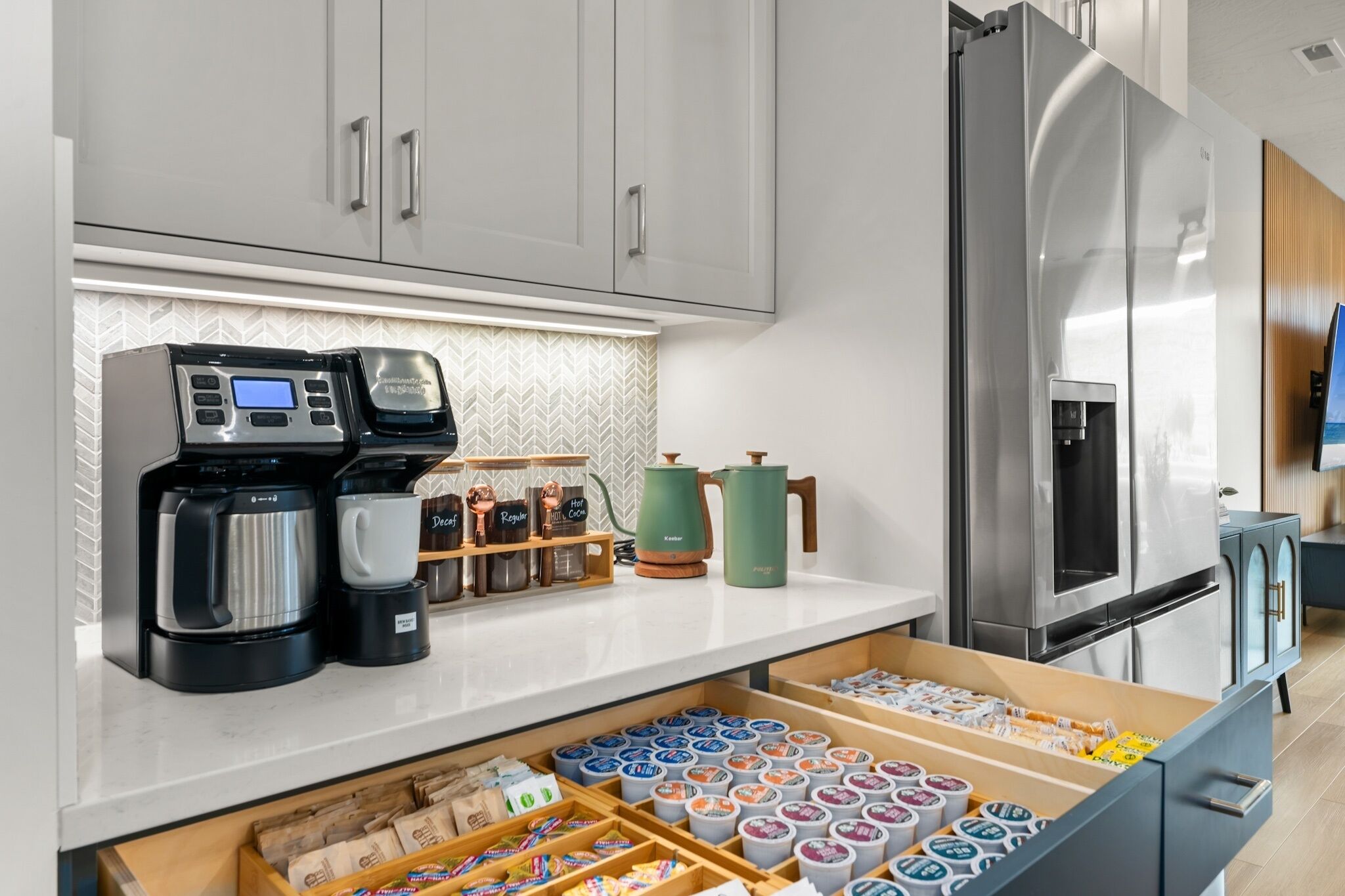 Une cuisine moderne équipée d’une machine à café, d’un distributeur d’eau et d’un réfrigérateur.