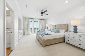 Un dormitorio con cama, mesitas de noche, ventilador de techo y vistas a través de la ventana.