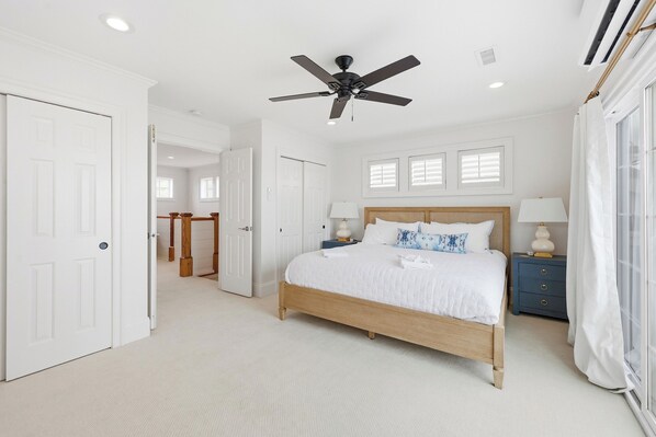 A bedroom with a bed, a ceiling fan, a nightstand, and a window with curtains.