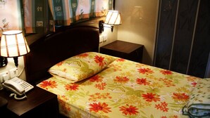 A hotel room with a bed, two bedside lamps, a telephone, and a wall with curtains. - LIS CHAIN HOSTEL (Kowloon)