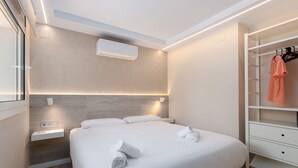 Une chambre d’hôtel moderne avec un lit bien fait, une armoire intégrée et un climatiseur fixé au mur.