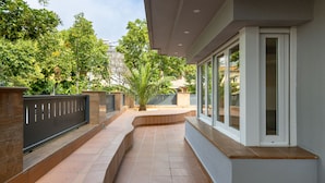 A modern outdoor corridor with a curved pathway, a stone wall, and a glass door leading to a covered area. - Mestral - Aparthotel with Swimming Pool (Vilassar de Mar)