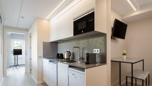 A modern kitchen with built-in appliances, a flat-screen TV, and a small dining area. - Ponent - Aparthotel with Swimming Pool (Vilassar de Mar)