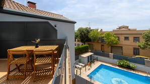 A rooftop terrace with a pool, wooden furniture, and a view of neighboring buildings. - Xaloc - Aparthotel with Swimming Pool (Vilassar de Mar)