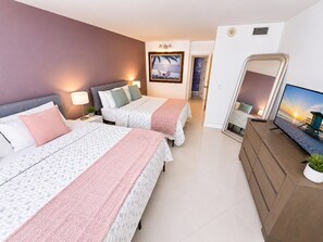 A hotel room with two beds, a TV, a dresser, and a painting on the wall.