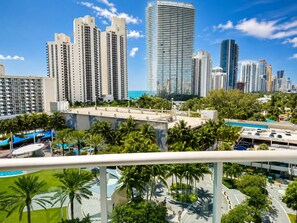 A high-rise building with a modern design, surrounded by palm trees and a clear blue sky.