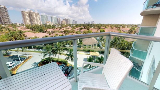 Un balcón con vista a un paisaje urbano, que incluye rascacielos y palmeras.