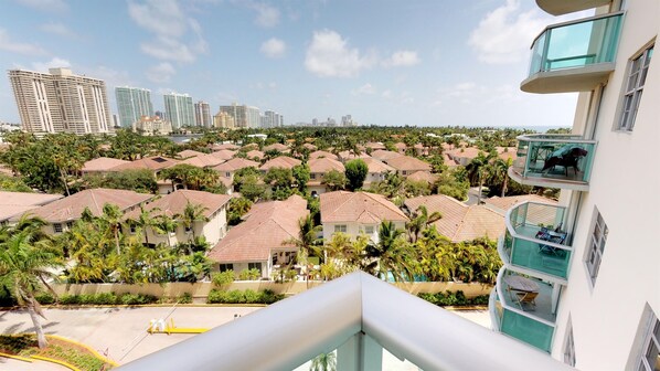 Zona residencial con varias casas, algunas con balcones, y vista a edificios altos en la distancia.