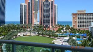 A high-rise hotel with multiple floors, a pool area with umbrellas, and a view of the ocean. - Ocean View Apartment  w/Parking in MIAMI-OR-805 (Sunny Isles)
