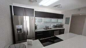 Una cocina moderna con electrodomésticos de acero inoxidable, dispensador de agua y microondas.