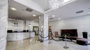 A hotel lobby with a marble reception desk, a chandelier, a Christmas tree, and seating areas. - PH11 Luxury Ocean View Apartment (Sunny Isles)