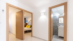 A hallway with a bed, a bathroom with a tiled wall, and a door leading to another room. - Cosy apartment near the beach in a quiet area · 240 UHC EL CRANC (Salou)