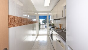 A modern kitchen with white cabinets, a built-in oven, and a large window. - Cosy apartment near the beach in a quiet area · 240 UHC EL CRANC (Salou)
