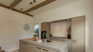 Una cocina moderna con una isla central, armarios de madera, un reloj en la pared y un jarrón con flores.