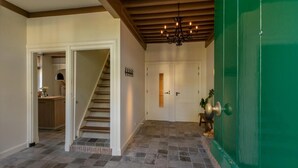 Un pasillo con una escalera, una puerta verde y una araña.