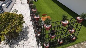 A rooftop garden with a neatly trimmed lawn, potted plants, and a seating area. - Noktel Resort Apartment  (Abuja)