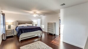 A bedroom with a large bed, bedside tables, a dresser, and a ceiling fan. - Spacious Home with Gorgeous Backyard Kitchen, Close to Top Shopping Destinations (Leander)