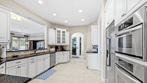 A modern kitchen with white cabinetry, stainless steel appliances, and a large island.