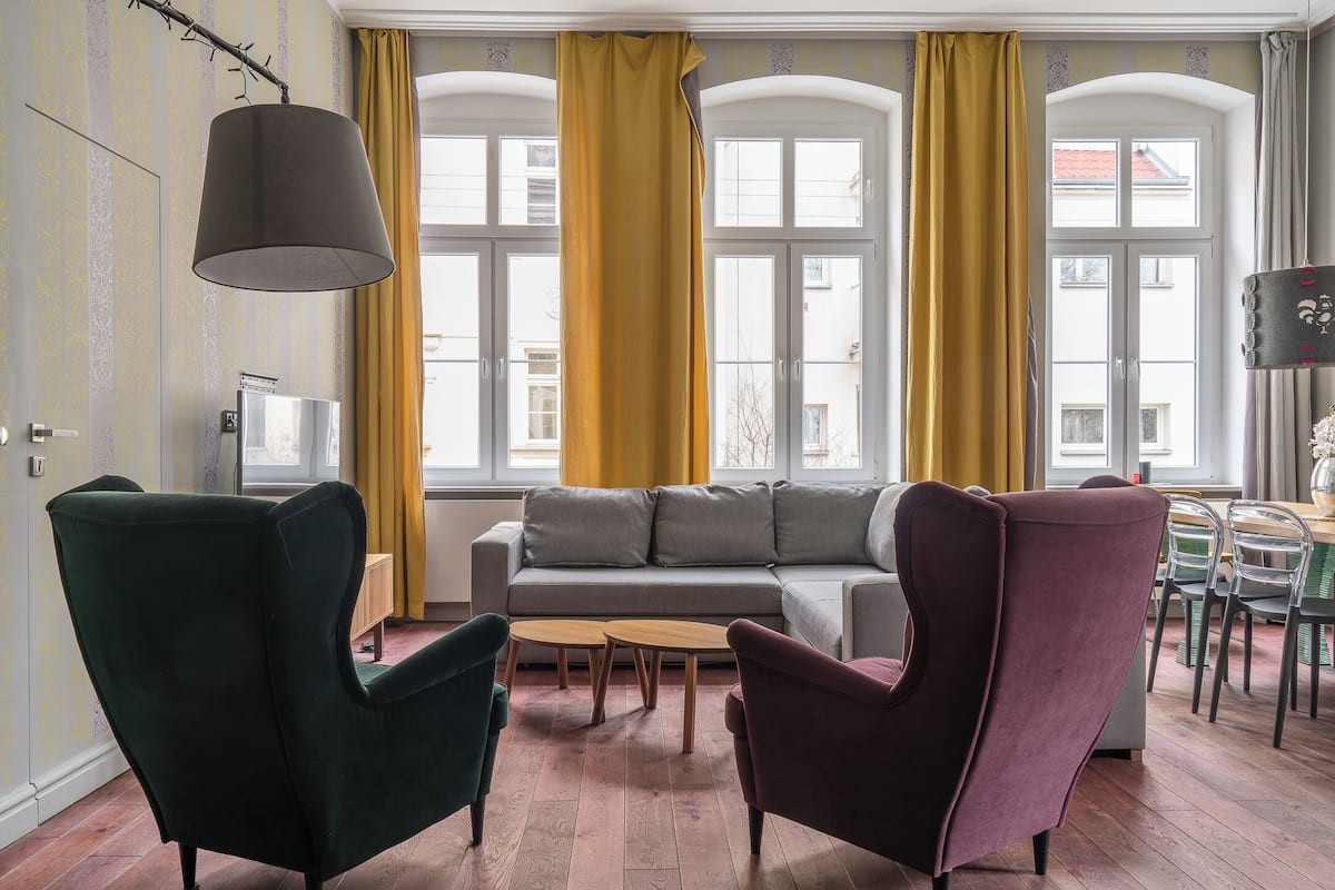 A living room with a sofa, two armchairs, a coffee table, and a dining area with chairs and a table.