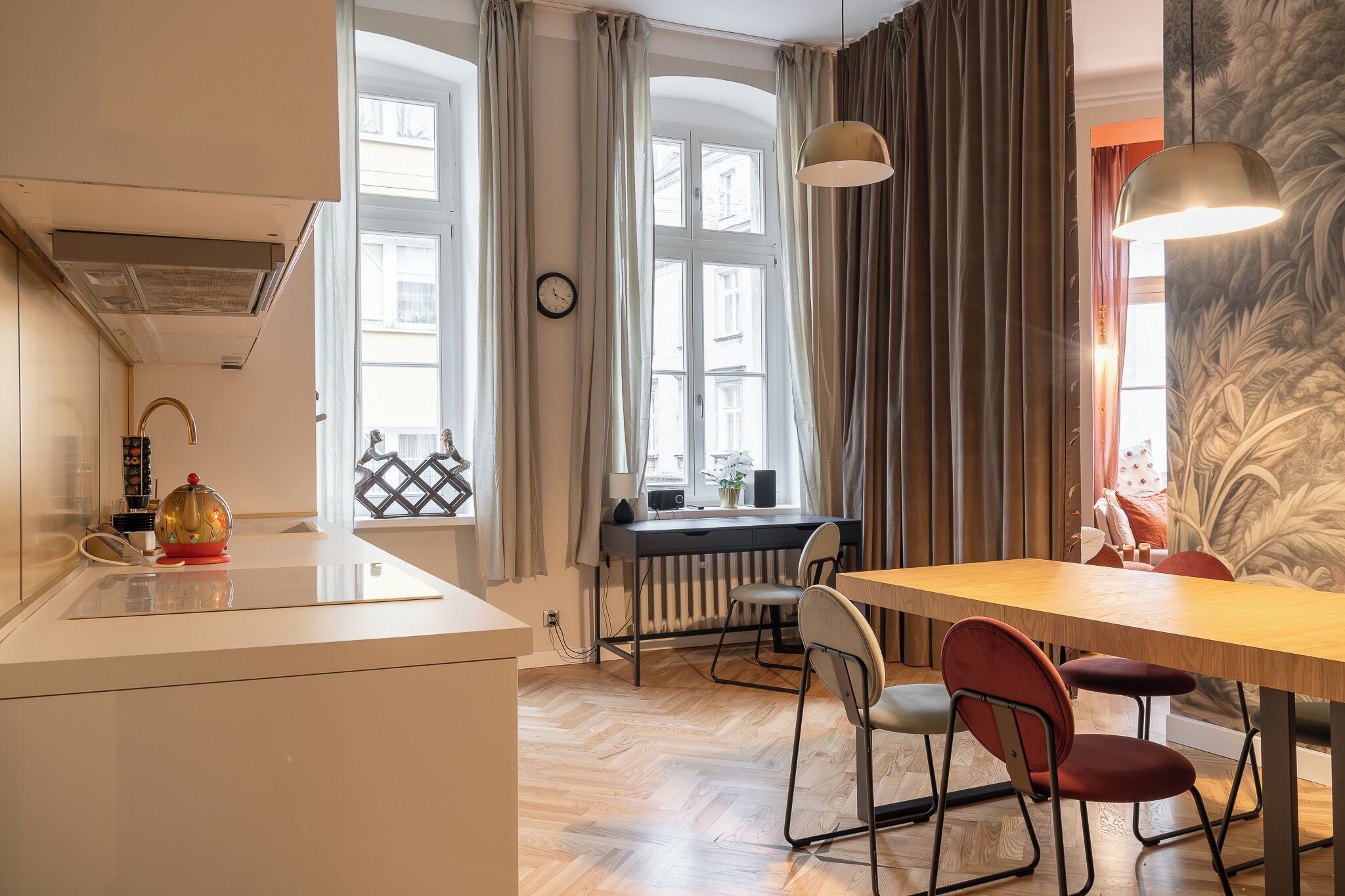 A modern kitchen with a dining area, large windows, and a radiator.