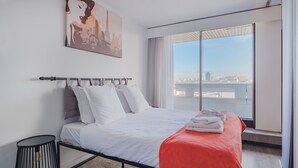 A modern hotel room with a large bed, a city view, and a painting on the wall. - Paris Expo 2 Residence (Paris)
