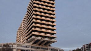 A tall, modern building with a unique slanted design, featuring multiple balconies and a circular base. - Paris Expo 2 Residence (Paris)