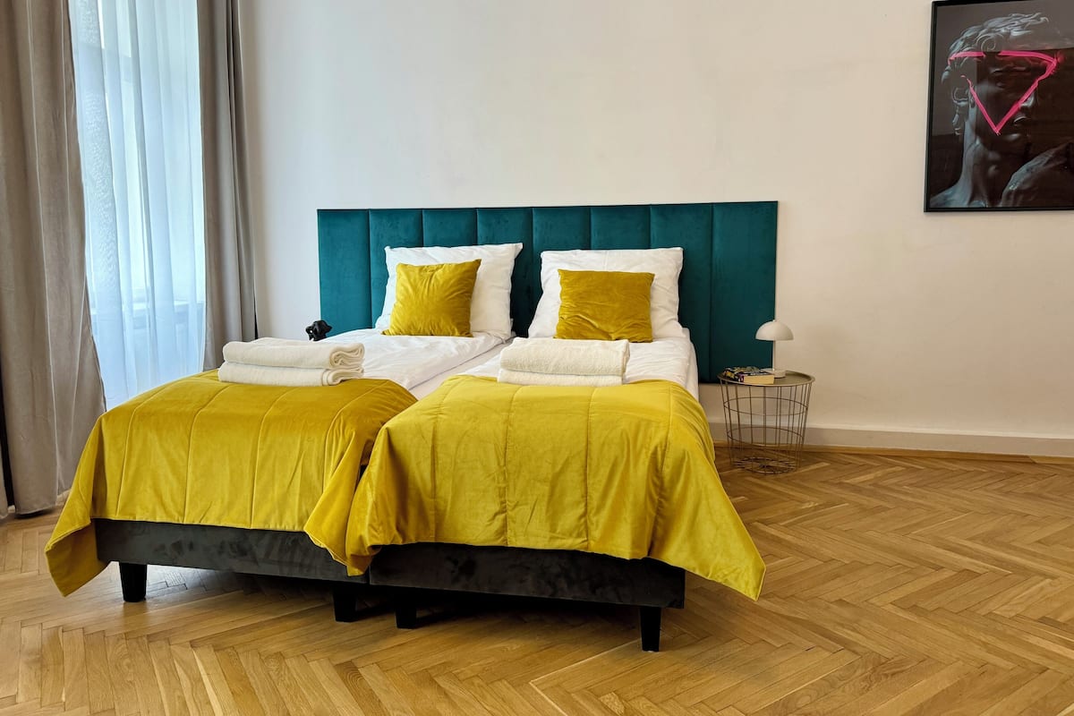 Un lit double avec une literie jaune, une tête de lit turquoise et un plancher en bois.
