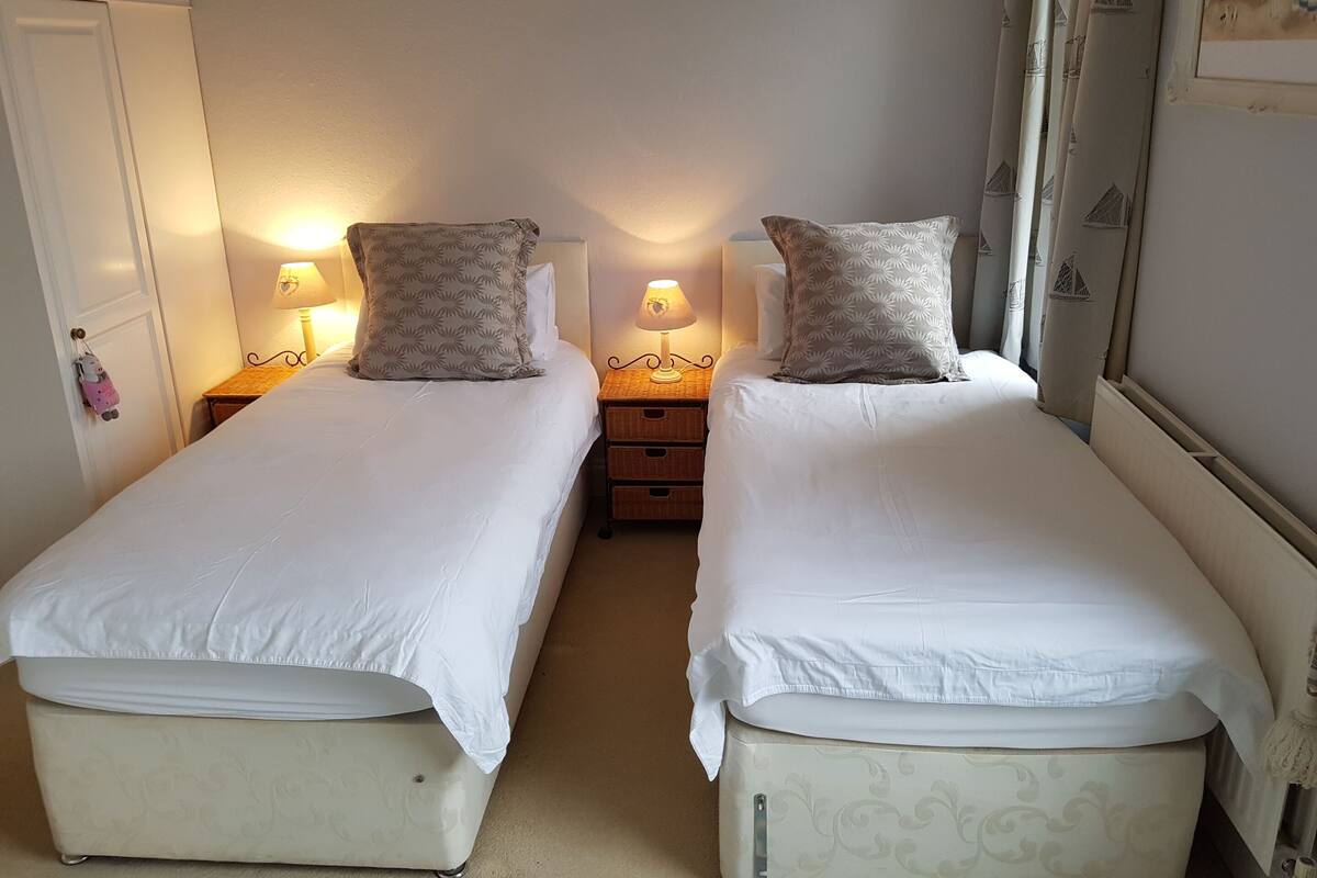 A twin room with two single beds, bedside tables with lamps, a wardrobe, and a mirror.
