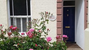 A building with a white brick facade, a blue door, and a window with shutters. - Cherry End bed and breakfast  (Chichester)