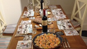A wooden dining table set with plates, glasses, cutlery, and a bottle of wine. - Cherry End bed and breakfast  (Chichester)